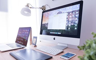 Photo of a desktop. There is a desktop Mac computer, a macbook and an iphone on the desk