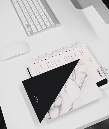 Photo of a desktop with a black and white notebook on it and a calendar